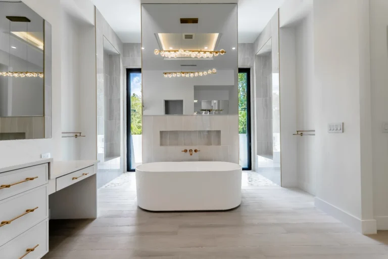 10th Ave NE primary bathroom with a freestanding tub, white vanities and gold fixtures