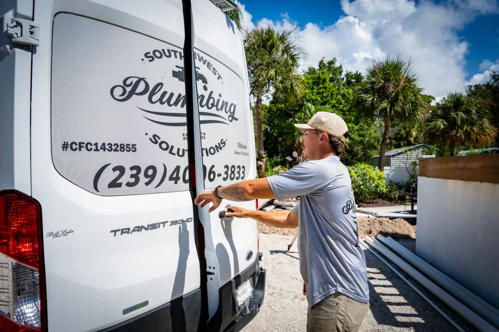 Southwest Plumbing Solutions crew member beside a branded van at an Englewood home construction site